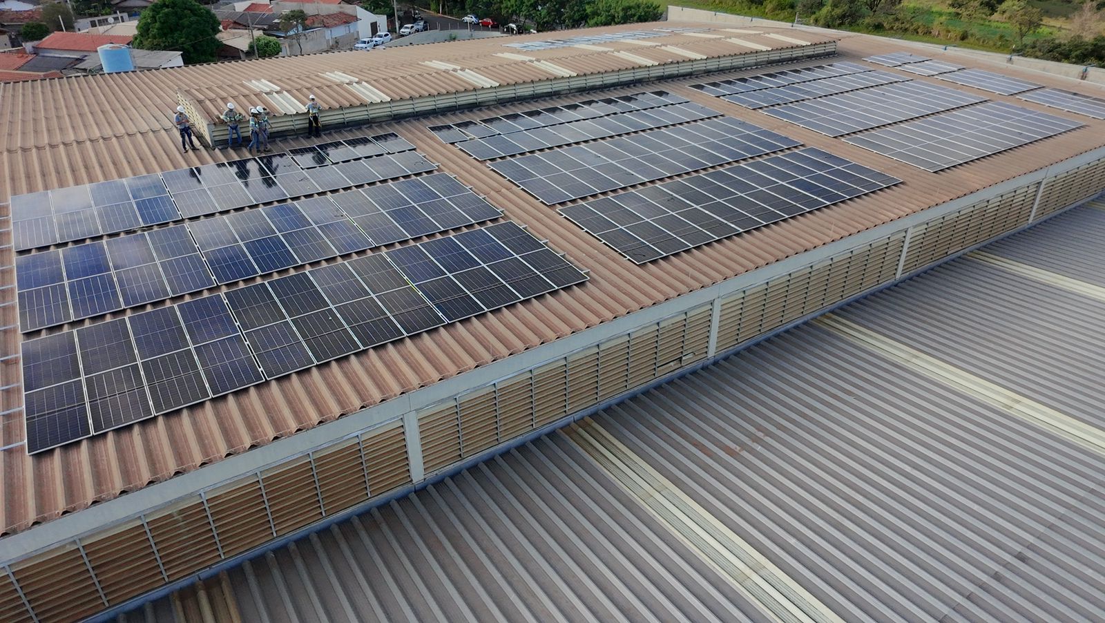 Equipe técnica instalando painéis solares em telhado comercial, projeto fotovoltaico em andamento