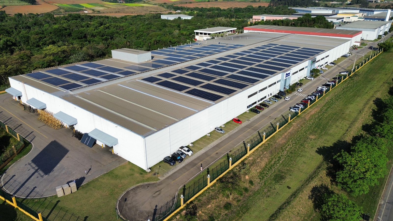 Usina fotovoltaica de grande porte em fábrica no distrito industrial, vista aérea com painéis solares no telhado